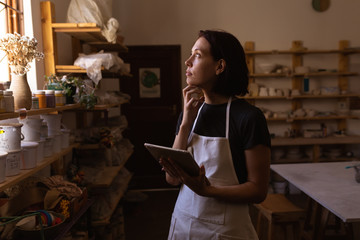Female potter using tablet in a pottery studio