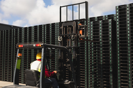 Factory worker driving a forklift truck outside a factory warehouse