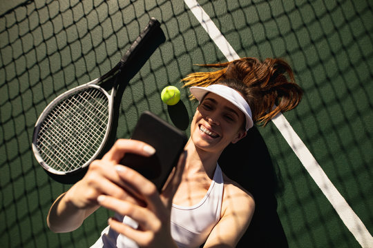 Woman taking a selfie at tennis court on a sunny day
