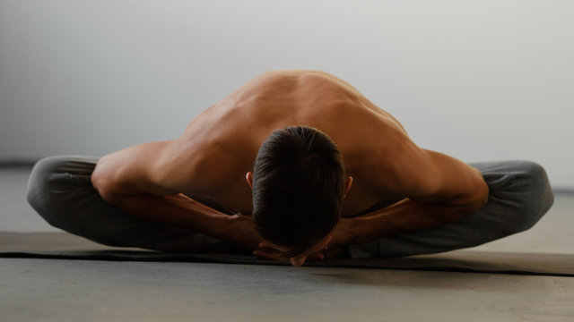 Beautiful sporty fit man practices yoga asana Baddha konasana - bound angle pose