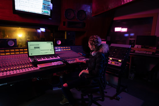 Female music producer working at the mixing desk in a sound studio