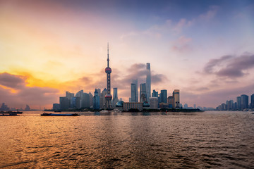 Fototapeta premium Sonnenaufgang hinter der modernen Skyline von Shanghai, Pudong Bezirk, mit den markanten Gebäuden und Wolkenkratzern, China