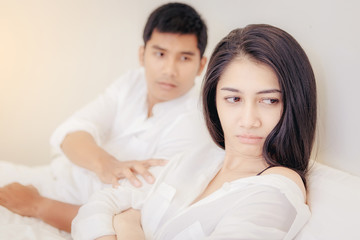 Frustrated young couple with serious relationship problems on the bed