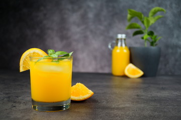A glass of fresh orange juice on grey background.