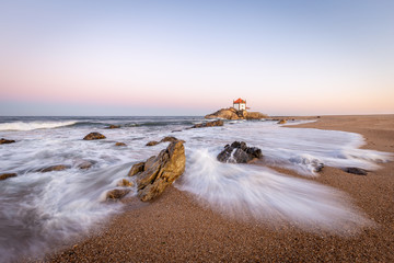 Sunrise at the beach with a church in the sea (Senhor da Pedra Chapel)