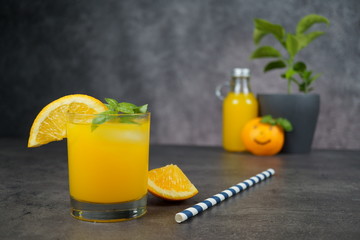 A glass of fresh orange juice on grey background.