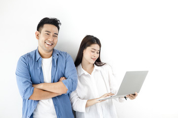 Happy Asian couple using laptop against white wall, lifestyle concept.