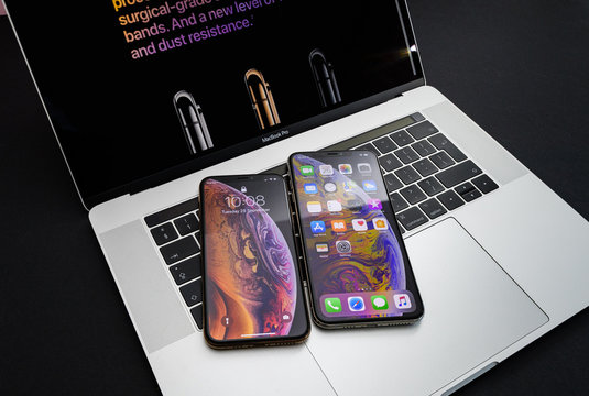 PARIS, FRANCE - SEP 25, 2018: New iPhone Xs and Xs Max smartphones model by Apple Computers close up photo on the keyboard of Apple MacBook pro laptop 15 inch apllpaper and home apps