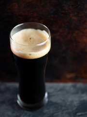 Fototapeta na wymiar A glass of dark craft beer porter on a rusty brown dark background