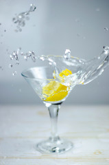Martini glass with lemon splash on light background