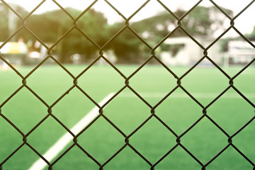 Fototapeta premium The iron grid fence of the football field in the evening