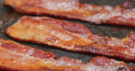 Fry bacon in pan in kitchen for breakfast