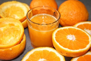 oranges and orange juice in glass on wooden table, a glass of fresh orange juice with oranges  in a gray place