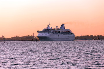 a cruise ship leaving harbor with Venice silhoutte in the background