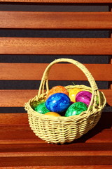 easter eggs in a basket  placed on a wooden bench