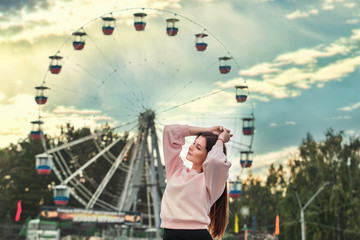 Young beautiful brunette woman happy in the city on the background of Park and Ferris wheel