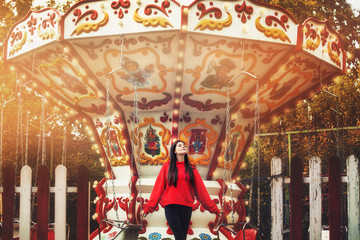 Young beautiful brunette woman happy in the Park on the background of bright colored carousel