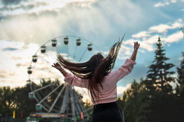 Young beautiful brunette woman happy in the city on the background of Park and Ferris wheel