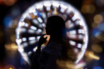 Young beautiful woman happy in the city at night on the background of Park and Ferris wheel