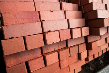 Pile of stacked new red bricks. Clay brick blocks ready for construction.