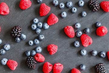 Himbeeren, Brombeeren und Heidelbeeren auf schwarzer Schieferplatte