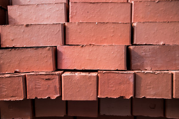 Obraz premium Pile of stacked new red bricks. Clay brick blocks ready for construction.