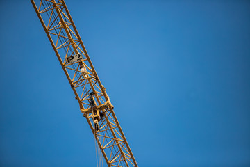 Construction site with cranes on sky background. Big yellow machinery construction crane tool of building industry for heavy lifting on blue sky background. Business engineering equipment modern
