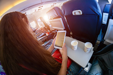 A girl in an airplane reading an e-book