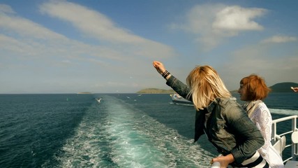 Two women feeding the seagulls by hand with bread on the deck of cruise ship. Greece. 4K