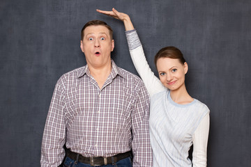 Studio shot of happy short woman and surprised tall man