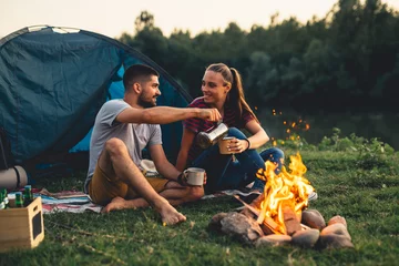 Poster Im Rahmen Glückliches Paar, das abends am Campingfeuer campt © cherryandbees
