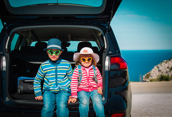 happy little boy and girl enjoy travel by car on sea coast