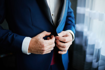 the groom straightens the wedding suit