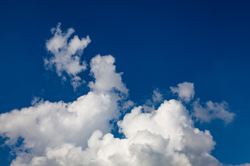 Snow-white cumulus clouds against a deep blue sky