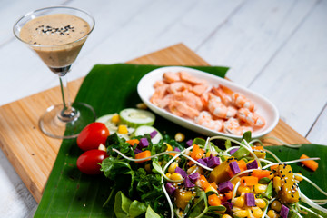 Fresh salad plate with shrimp, salmon, tomato and mixed greens  on wooden background .