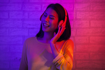 Fashion girl with red and blue light happy and relax with music from head phone 