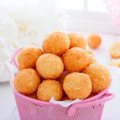 Cheese balls in a pink basket on a white table, square