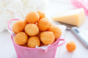 Homemade cheese balls in a pink basket on a white table, horizontal
