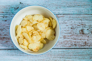 Potato chip in the white bowlon the wood grunge blue paint color, Potato fried snack on wood table 