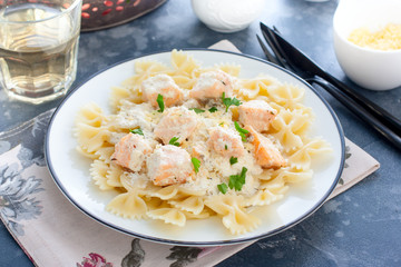 Farfalle with salmon in a creamy sauce and a white plate, horizontal