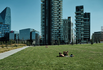 boy or man taking sun (darkening of skin) tan in the new park in Porta nuova in Milan during summer season - Lombardy. Italy.