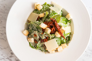 Cesar salad with bacon cheese on white plate in luxury restaurant.