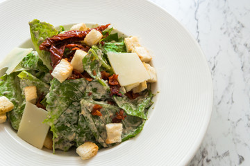 Cesar salad with bacon cheese on white plate in luxury restaurant.
