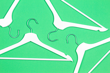 White wooden hangers on pastel green background. Shopping, sale, promo, social media, new season concept