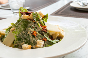 Cesar salad with bacon cheese on white plate in luxury restaurant.