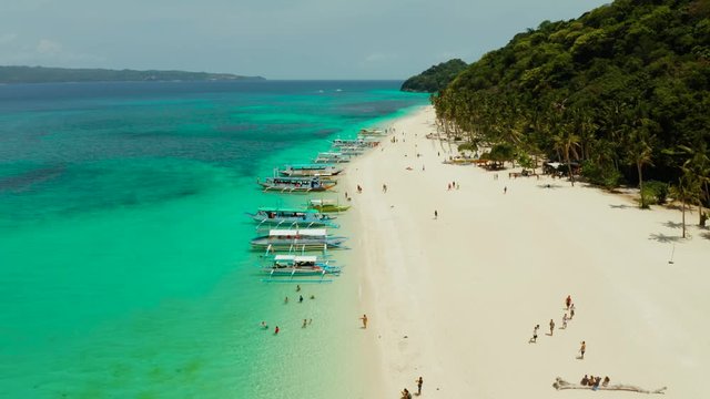 Tropical white sand beach, near the blue lagoon and corall reef from above, Boracay, Philippines. Sandy beach with tourists. Summer and travel vacation concept.