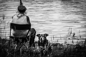 An alone woman and her guardian dog are fishing on the Cassière lake