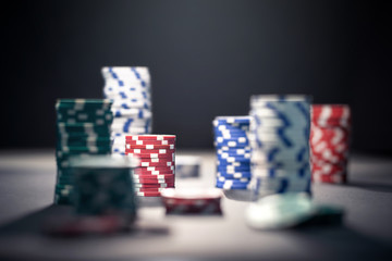 Casino poker chips in dramatic dark shadow or at night in spotlight. Stack of game money. Risk, luck and betting concept. Gambling problem and addiction.