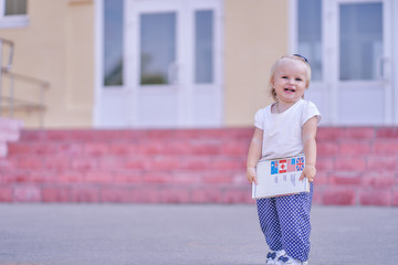 infant girl on the background of school stairs with a book. copy space