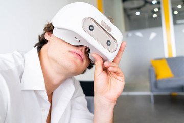 Man wearing virtual reality goggles in modern bright co-working office. the VR experience.